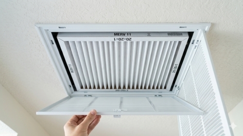 Homeowner in Brandon FL replacing a 20x20x1 air filter in a ceiling return vent.