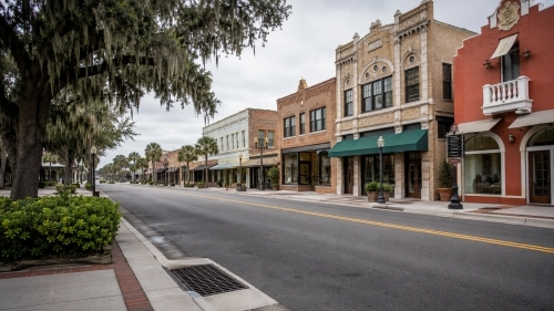 Historic 1920s brick storefronts and buildings along a street lined with oak trees and Spanish moss in downtown Lake Wales FL.